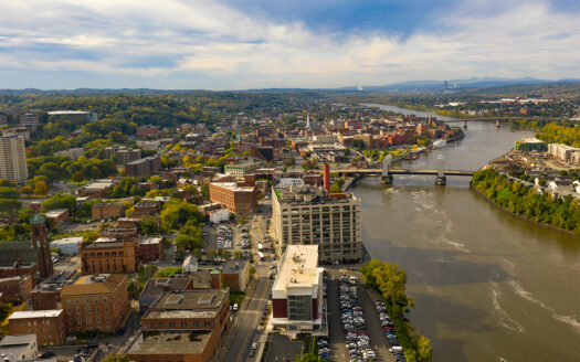 Aerial view of downtown Troy, NY, with brick buildings, early fall trees and the Hudson River