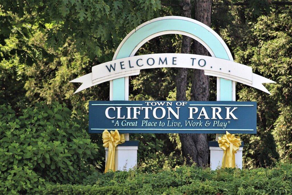 Town of Clifton Park welcome sign with yellow ribbons, set in front of trees and hedges